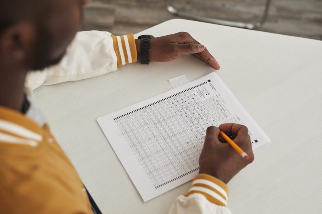 Focused student marking answers on a multiple choice exam sheet in a classroom setting.